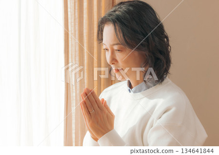 一位中年婦女在家中為逝者祈禱。 134641844