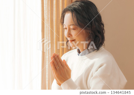 一位中年婦女在家中為逝者祈禱。 134641845