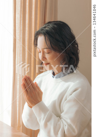 一位中年婦女在家中為逝者祈禱。 一位中年婦女在家中為逝者祈禱。 134641846