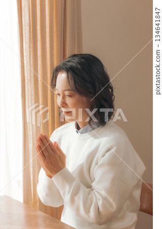 一位中年婦女在家中為逝者祈禱。 134641847