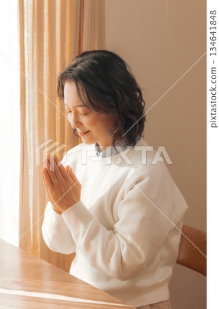 A middle-aged woman praying for the deceased at home 134641848