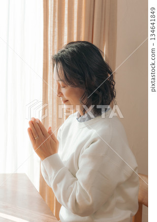 一位中年婦女在家中為逝者祈禱。 134641849