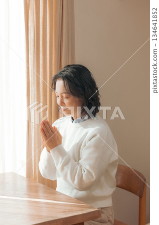 一位中年婦女在家中為逝者祈禱。 134641852
