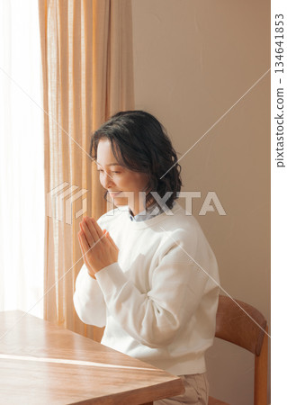 一位中年婦女在家中為逝者祈禱。 一位中年婦女在家中為逝者祈禱。 134641853