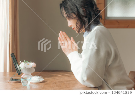 A middle-aged woman praying for the deceased at home A middle-aged woman praying for the deceased at home 134641859