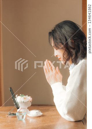 一位中年婦女在家中為逝者祈禱。 一位中年婦女在家中為逝者祈禱。 134641862