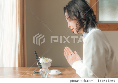 一位中年婦女在家中為逝者祈禱。 134641865