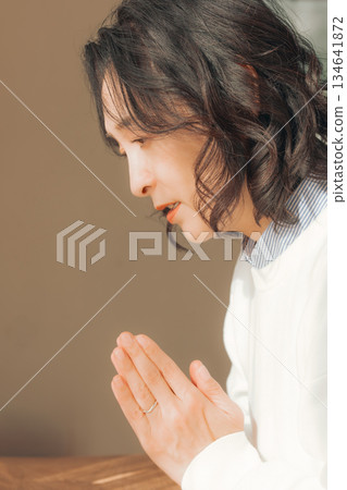 一位中年婦女在家中為逝者祈禱。 一位中年婦女在家中為逝者祈禱。 134641872