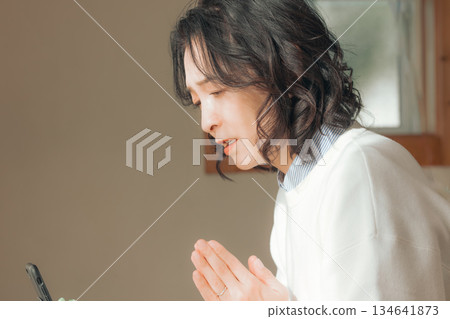 一位中年婦女在家中為逝者祈禱。 134641873