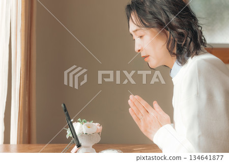 一位中年婦女在家中為逝者祈禱。 134641877