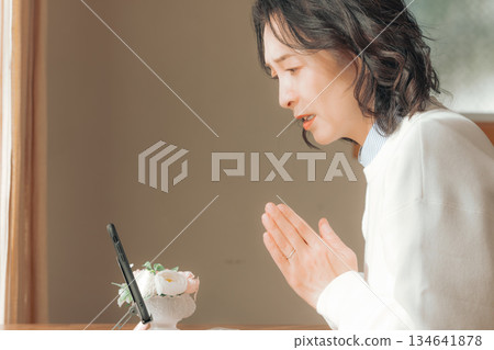 一位中年婦女在家中為逝者祈禱。 一位中年婦女在家中為逝者祈禱。 134641878