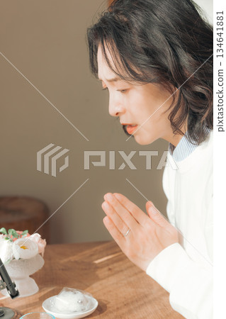 一位中年婦女在家中為逝者祈禱。 一位中年婦女在家中為逝者祈禱。 134641881