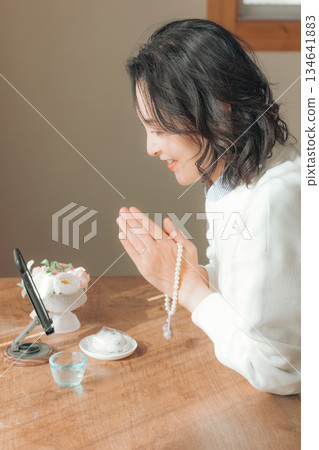 一位中年婦女在家中為逝者祈禱。 134641883