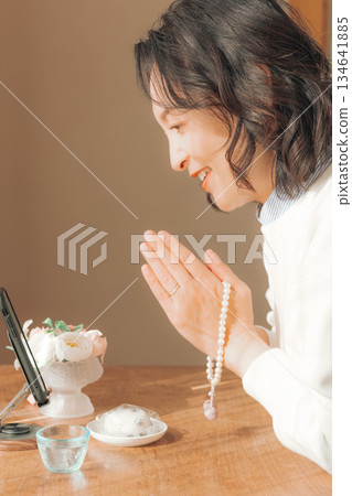 A middle-aged woman praying for the deceased at home A middle-aged woman praying for the deceased at home 134641885