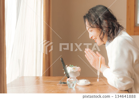 A middle-aged woman praying for the deceased at home A middle-aged woman praying for the deceased at home 134641888
