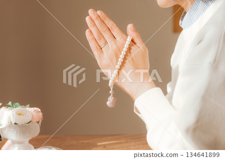 A middle-aged woman praying for the deceased at home 134641899