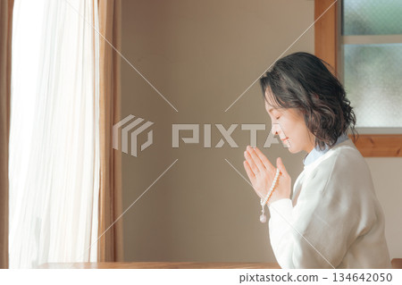 一位中年婦女在家中為逝者祈禱。 一位中年婦女在家中為逝者祈禱。 134642050