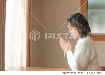 A middle-aged woman praying for the deceased at home 134642051
