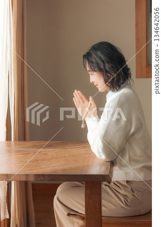A middle-aged woman praying for the deceased at home A middle-aged woman praying for the deceased at home 134642056
