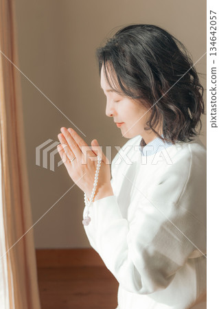 A middle-aged woman praying for the deceased at home A middle-aged woman praying for the deceased at home 134642057