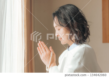 一位中年婦女在家中為逝者祈禱。 一位中年婦女在家中為逝者祈禱。 134642060