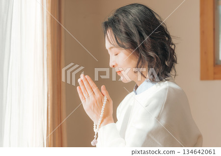 A middle-aged woman praying for the deceased at home 134642061