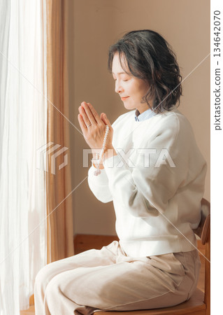 A middle-aged woman praying for the deceased at home 134642070