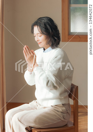 一位中年婦女在家中為逝者祈禱。 一位中年婦女在家中為逝者祈禱。 134642072