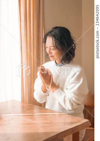 一位中年婦女在家中為逝者祈禱。 一位中年婦女在家中為逝者祈禱。 134642095