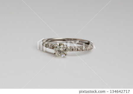 A white gold engagement ring featuring a round-cut diamond, with a pave diamond band for added brilliance. 134642717