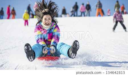 女子乘坐塑膠雪橇在雪地上滑行 134642813
