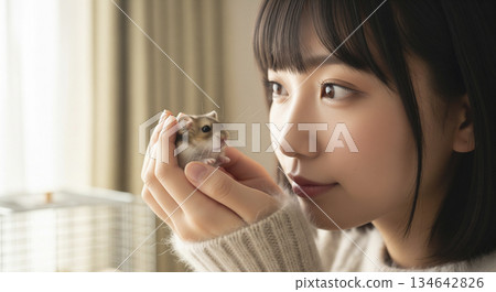 一位女士正在撫摸一隻倉鼠 一位女士正在撫摸一隻倉鼠 134642826