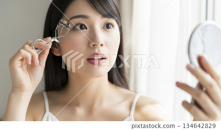 Woman curling her eyelashes 134642829