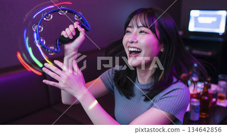 一位女士在卡拉OK廳興致勃勃地演奏鈴鼓。 一位女士在卡拉OK廳興致勃勃地演奏鈴鼓。 134642856