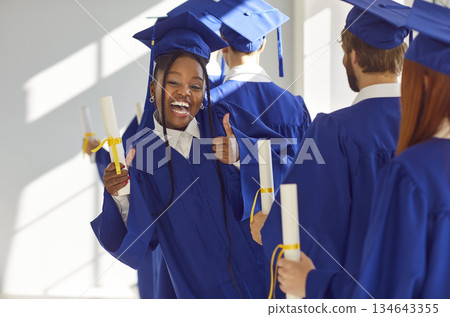 Black Female Graduate Celebrates Success with Diploma and Thumbs Up 134643355