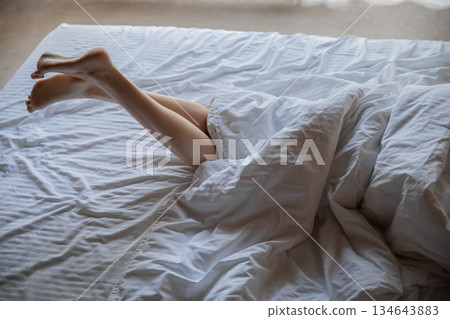 Female feet in bed. Young woman with beautiful legs in bedroom Female feet in bed. Young woman with beautiful legs in bedroom 134643883