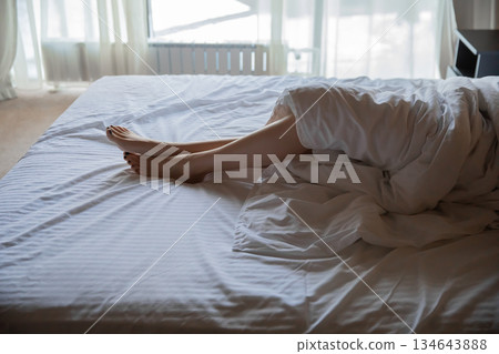 Female feet in bed. Young woman with beautiful legs in bedroom Female feet in bed. Young woman with beautiful legs in bedroom 134643888