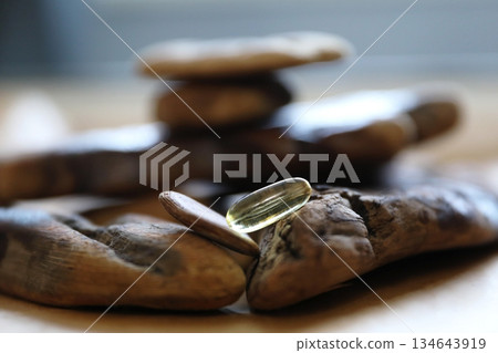 Transparent omega 3 capsule on natural driftwood. Fish oil supplement for healthy diet. Nutrition and health concept. Transparent omega 3 capsule on natural driftwood. Fish oil supplement for healthy diet. Nutrition and health concept. 134643919