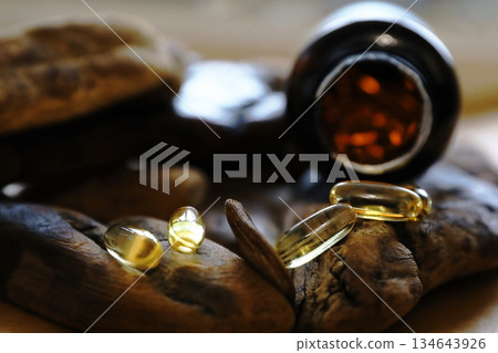 Omega 3 pills spilling from a bottle onto driftwood. Natural health supplement concept for advertising and pharmaceutical packaging. 134643926