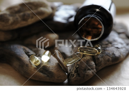 Omega 3 fish oil capsules and a brown bottle on wood surfaces. Nutritional supplement for healthy lifestyle. Healthcare and wellness concept. 134643928