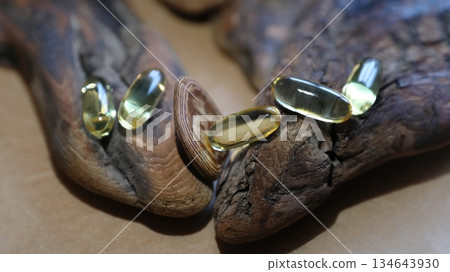 Five golden omega 3 capsules on wooden bark. Health supplement and nutrition concept. Pills for heart health. 134643930