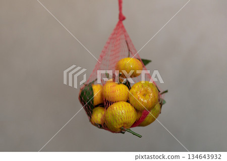 Mandarins with leaves in a red netting Mandarins with leaves in a red netting 134643932