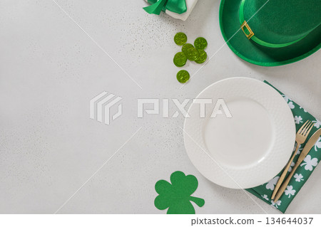 St Patricks Day banner with white plate, cutlery, table setting, gift, leprechaun hat and clover leaves on white background. View from above. Copy space. 134644037
