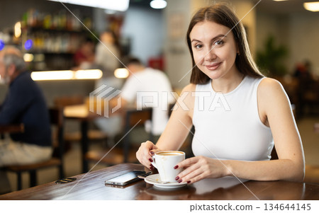 Girl whiles away time and drink coffee in cafe 134644145