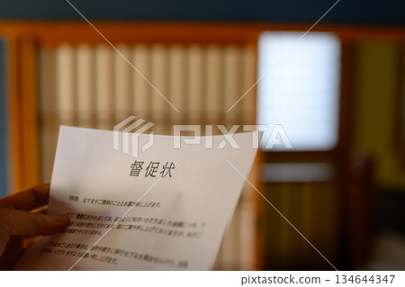 一名男子在日式房間裡拿著一封索賠信。 134644347