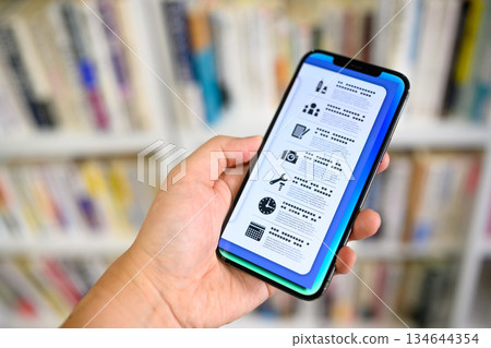 在書架前使用智慧型手機 134644354