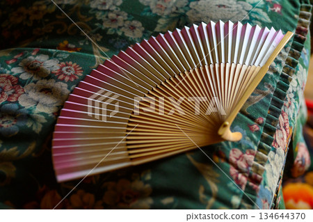 A folding fan placed on a green cloth 134644370