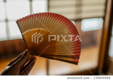 日式房間裡，雙手拿著扇子。 134644408