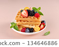 Stack of golden waffles topped with fresh berries and mint leaves on white plate. Breakfast or brunch concept 134646886
