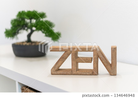 A wooden sign spelling 'ZEN' sits on a shelf beside a small bonsai tree, creating a calming atmosphere in a modern indoor space 134646948